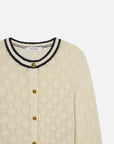 The Rookie Cardi by FRAME is a cream lightweight knit cardigan with a textured pattern, gold buttons, and a round neckline trimmed in black and white stripes.