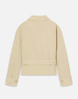 The Uniform Trench by FRAME shown from the back: beige, lightweight, cropped design with a straight hem, long sleeves with buttoned cuffs, flat collar, and waistband detail. Set against a plain white background.