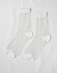 Unified Sheer Dot Socks: sheer anklets featuring a textured polka dot design with solid white toe, heel, and cuff, displayed flat on a white surface.