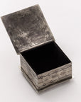 The Small Stamped Box w/ Turquoise Cross by J Alexander Rustic Silver features a square silver metal design with an intricate pattern, hinged lid, and a rich dark interior—ideal for keepsakes and Southwestern decor.