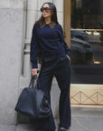 White + Warren cashmere contrast collar sweater on woman in sunglasses, relaxed city street setting near stone wall.