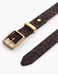 A close-up of the Rag & Bone X Boyfriend Belt, a menswear-inspired calf hair accessory with a gold buckle, pointed end, and rich brown and black leopard print.