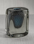 The Zodax Crystal Bloom Vase is a square, clear glass vase with rounded edges, a blue-tinted center, and textured bubbles inside—ideal as premium home décor on a light gray surface with a subtle background.