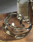 The Zodax CH-7877 Viento Glass Bowl, with its abstract organic shape, sits on a wooden tray beside Barr Hill Gin and a metal shaker, creating striking sculptural home decor for any space.