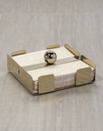 The Zodax Cocktail Napkin Holder Gold features a central horizontal bar with a round gold knob and holds stacked napkins elegantly on a light textured surface—an ideal accessory for any setting.