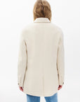 A person with long, light brown hair is shown from the back, wearing the Rag & Bone zoe wool blazer in cream and blue jeans against a plain white background.