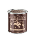 The G&W Soy Candle by Faire comes in a brown tin and features a cowboy riding between cacti. Scent notes of tobacco and worn leather evoke nostalgic joy. The text reads "Made in the USA.
