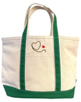 The Hey Good Lookin' tote by Faire features beige canvas, green handles and trim, plus a gold and red heart embroidered on the front—perfect for essentials or as a chic makeup bag.
