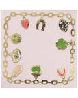 The Faire Cocktail Napkin is a fun square napkin featuring a decorative gold chain border, perfect for any occasion. Symbols like a horseshoe, heart, eye, and clover elegantly adorn the perimeter in gold on a light pink background.