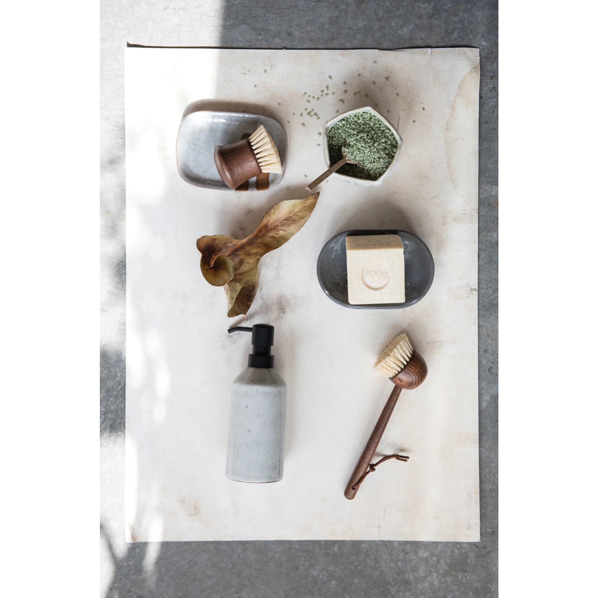Top view of an assortment of eco-friendly bath products including soap bars, brushes, and liquid soap in stone and metal containers, arranged on a marble surface in a Scottsdale Arizona bungalow.