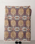 A person stands behind the Bloomingville Cotton Throw / Tibetan Tigers, featuring stylized tiger faces and geometric shapes—only their feet show below this boho Cotton Slub blanket.