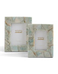 The HCM020-AZS2 Amazonite Frames by Two's Company feature two rectangular frames with light blue and beige marble patterns, inspired by amazonite. Each unique frame displays a "Tozai Home" logo card and stands upright on a white background.