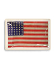 The Faire American Flag Glass Tray features 50 white stars and 13 red and white stripes, framed with a white border. This rectangular glass tray offers subtle reflections, making it striking patriotic decor.