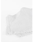 Two folded Antik Matelasse Coverlets by Matteo, featuring a subtle crinkled jacquard weave, rest on a white surface, adding depth and texture.