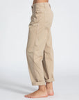 A person wearing ASKK Slim Chino pants in tan.