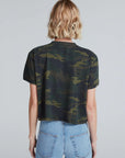 A person with short blonde hair is seen from the back, wearing the ASKK Shrunken Boy Tee in camouflage and high-waisted blue jeans against a plain light gray background.