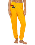 A model showcases Aviator Nation’s logo - womens sweatpants in bright yellow, featuring a red and black geometric "A" on the left hip. Only her lower torso and legs are visible as she stands barefoot against a white backdrop.