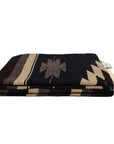 The Faire XL Mexican Diamond Blanket in brown and black features geometric patterns and fringed edges, inspired by classic designs, shown folded against a plain white background.
