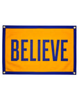The Oxford Pennant Believe Camp Flag 16x24 is a rectangular yellow and blue flag with a blue border, "BELIEVE" in bold blue letters at the center, a screen-printed design, and metal grommets in each corner.