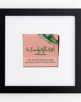A framed artwork featuring a pink napkin from The Beverly Hills Hotel and Bungalows, with partial green palm leaves, encased in the **Match South Art Square Blk Frame**. The text on the napkin reads "On Sunset Boulevard, Beverly Hills, California." The frame is black with a white mat background, encased in clear acrylic for added elegance.