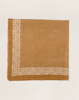 The Big Bandana by The Great Inc. is a square vintage cotton bandana with a brown background, white floral border, and small white floral patterns in the center, shown laid flat on a light textured surface.