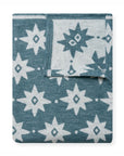 The Faire Big Sky Lightweight Blanket is shown folded, featuring a blue background with a white geometric star and diamond pattern, displaying both the front and back sides of the fabric.