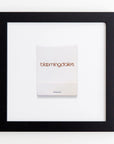 A framed white matchbook with “Bloomingdale's” written in brown text on it, centered on a white background. The Art Square Blk Frame by Match South has a minimalist design, allowing the prints to stand out against the clear acrylic cover, adding an elegant touch.