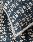 Close-up of the Faire Blossom Block Print Blanket, crafted in blue fabric with a white floral pattern and striped edging, featuring intricate hand-stitched details.