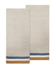 The Caravan Normandy Natural Towel Set-2 features two beige cloth napkins with blue and mustard yellow borders, inspired by classic French kitchen towels. They are shown slightly overlapping for an elegant, timeless appeal.