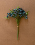 The CHAL1047 Blueberry Bundle by Kalalou, Inc features green stems with clusters of dark blue berries and fern-like leaves, all secured with a rubber band and displayed on a plain brown background.
