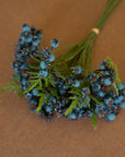 The Kalalou, Inc Blueberry Bundle features artificial berries, green leaves, and long stems tied with a small band, displayed on a brown surface.