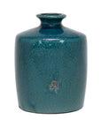 The Import Collection's Newton Short Vase is a small, cylindrical clay vase with a short neck, wide rounded body, and mottled teal glaze featuring a beige spot near the center.
