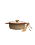 The Creative Co-op DF7975 Brie Baker with a lid and two handles features a beige and brown glazed, textured ceramic finish. A small bamboo spreader is tied to one handle, perfect for serving.