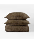 The Bruno Duvet Cover Queen by Amity Home, featuring brown fabric with thin vertical white stripes, is crafted from soft cotton and displayed folded with matching pillows against a plain white background for modern elegance.