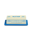 Fishes Eddy Butter Stick Butter Dish holding a stick of butter with wrapper measurement markings visible.