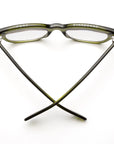 A pair of Caddis Miklos Heritage Green eyeglasses with thick frames sits upside down, arms crossed at the bottom. "PORT" is above the left lens and "STARBOARD" above the right, all set against a white background.