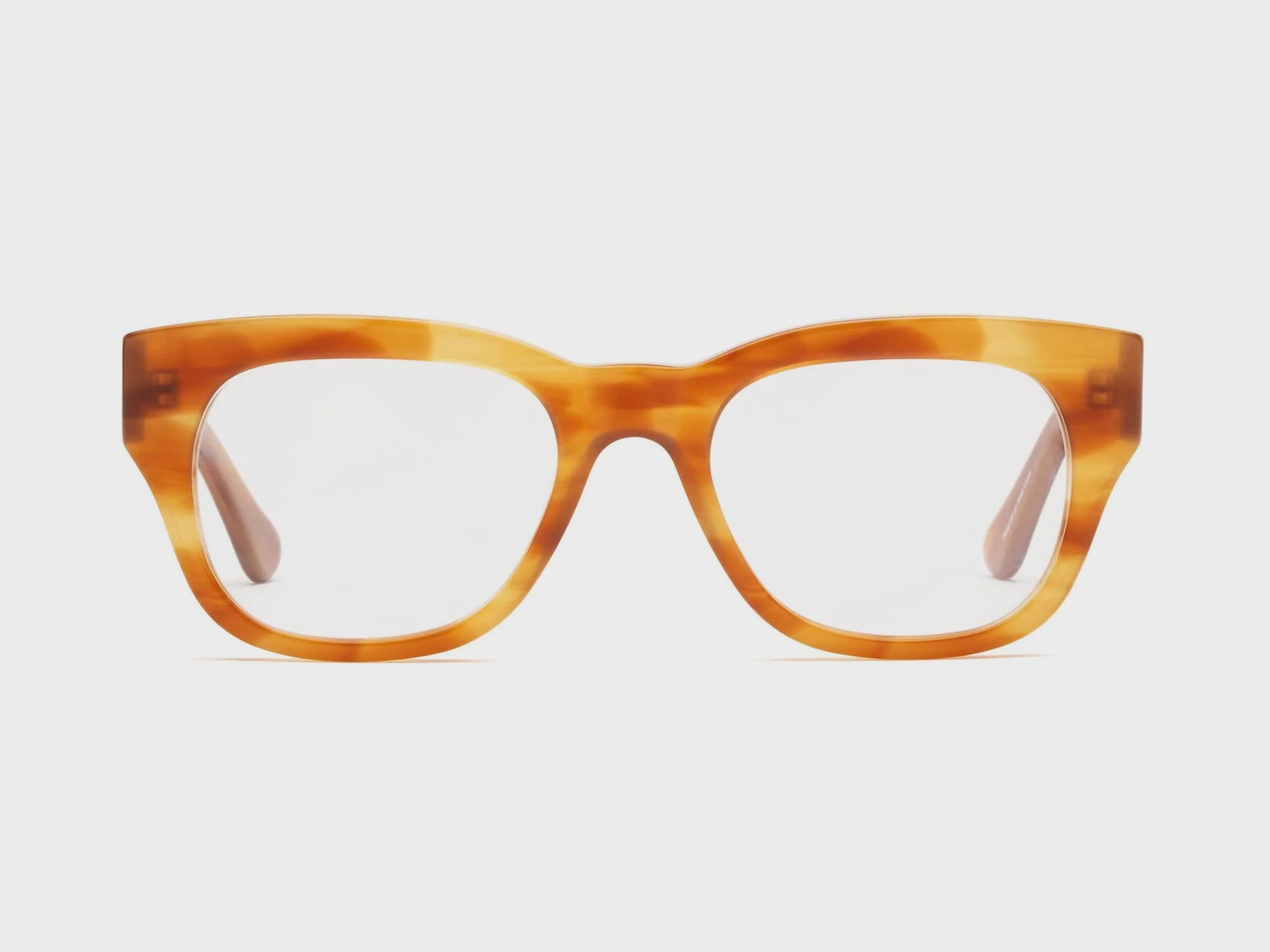 A pair of oversized, translucent amber-colored square frame glasses with a thick frame, isolated on a white background from Caddis Miklos Tabby.