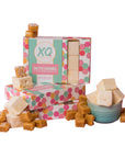 Boxes of Faire Salted Caramel Marshmallows are stacked, surrounded by allergy-friendly marshmallows and caramel candies, with a bowl of fluffy salted caramel cubes placed in front.