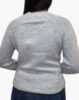 A person is shown from the back against a white background, wearing White + Warren's Cashmere Luxe Henley in light grey with dark blue jeans.