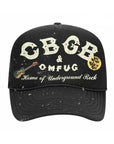 The MadeWorn Hat by Made Worn is a black cap with white speckles, a front patch reading “CBGB & OMFUG Home of Underground Rock,” a small guitar graphic, yellow “Sex, Drugs & Rock ’n’ Roll” button, and an adjustable back strap.