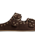 The CEDAR by Beek is a brown suede slide sandal with arch support, two adjustable straps featuring gold eyelets and large round buckles, plus a comfortable cork footbed.