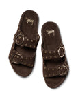 The Beek CEDAR sandals feature dark brown suede, two wide adjustable straps with large silver buckles and metal eyelet accents, a flat comfortable sole, and the brand name "Beek" printed on the insole.