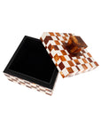 The Camiro Short Box by The Import Collection features a brown, amber, and white checkerboard pattern with a large geometric handle. Its open lid reveals a black interior, making it ideal decorative storage for your space.
