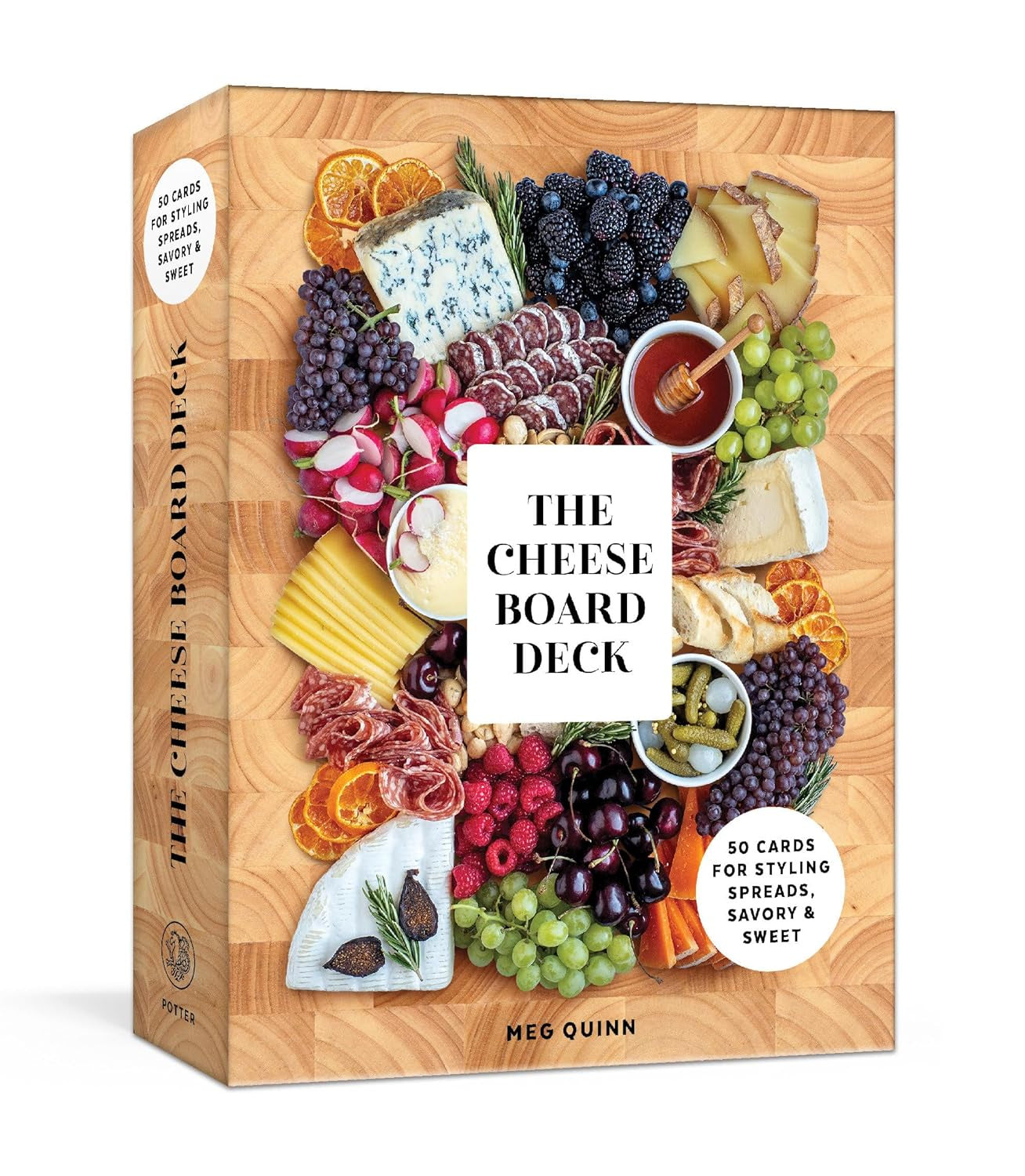 Book cover titled &quot;The Cheese Board Deck&quot; by Random House featuring an array of cheeses, fruits, and meats artistically arranged around the title text. Bright colors and diverse textures are visible, showcasing exquisite food styling.