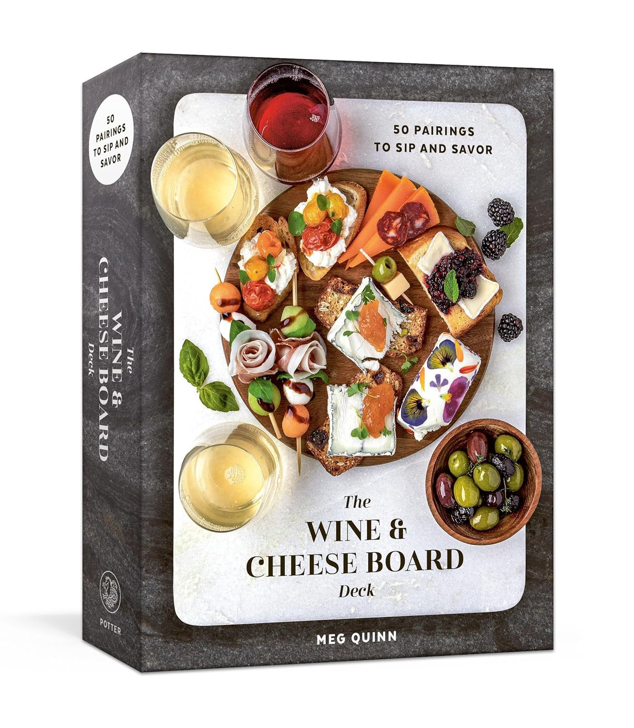 Photo of a book titled &quot;Wine &amp; Cheese Board Deck&quot; by Random House, displaying various cheese boards with wine glasses, arranged around the book&#39;s cover, highlighting wines under $25 and their pairings.