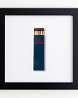 A black-framed picture containing a minimalist design showcases a dark blue matchbox with the word "Cipriani" in red and a red logo above it. The Match South Art Square Blk Frame, encased in clear acrylic, is centrally aligned against a white background.