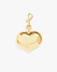 The Clare Vivier Grand Mylar Heart FOB, a gold heart-shaped charm with a shiny surface and top clasp, is perfect as a keychain or elegant bag accessory, displayed against a plain white background.
