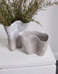 Wavy beige and white Claribel Vase Short by Accent Decor with green branches on a white tabletop.