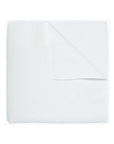 The John Robshaw Coverlet Queen is a folded white quilt featuring a textured pattern and reversible design, with one corner turned down to display the organic cotton underside.