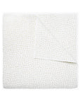 The John Robshaw Coverlet Queen is a white organic cotton quilt with a subtle stitched pattern, neatly folded to reveal its reversible design.